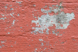 Closeup of chipped paint on old red wall